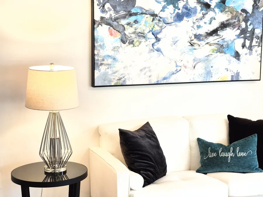 White loveseat styled with abstract artwork and a contemporary side table