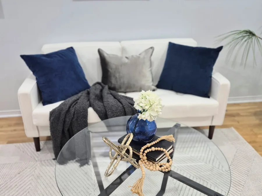 Staged sitting area with navy pillows and a round glass coffee table